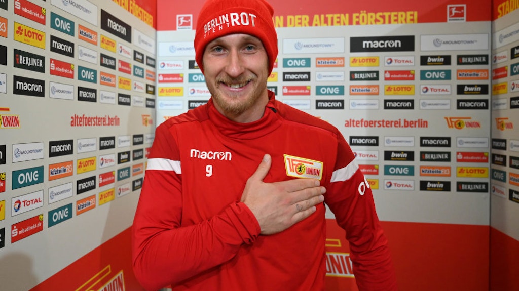 Hand aufs Herz und Mütze drauf: Sebastian Polter grinst vor Freude.