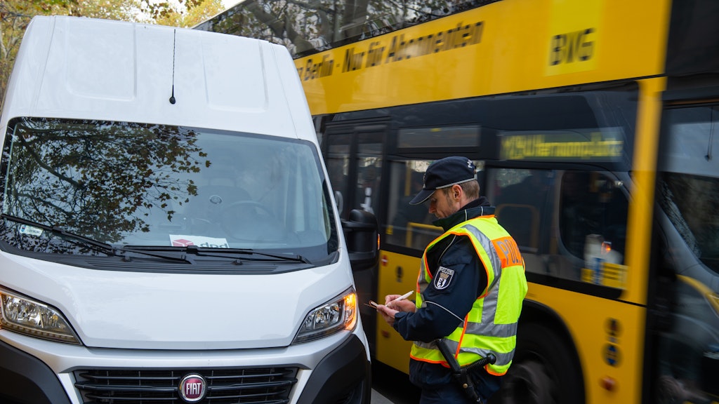 Ein Polizist schreibt einen Lieferwagen auf, der in Berlin-Charlottenburg in zweiter Reihe parkt.