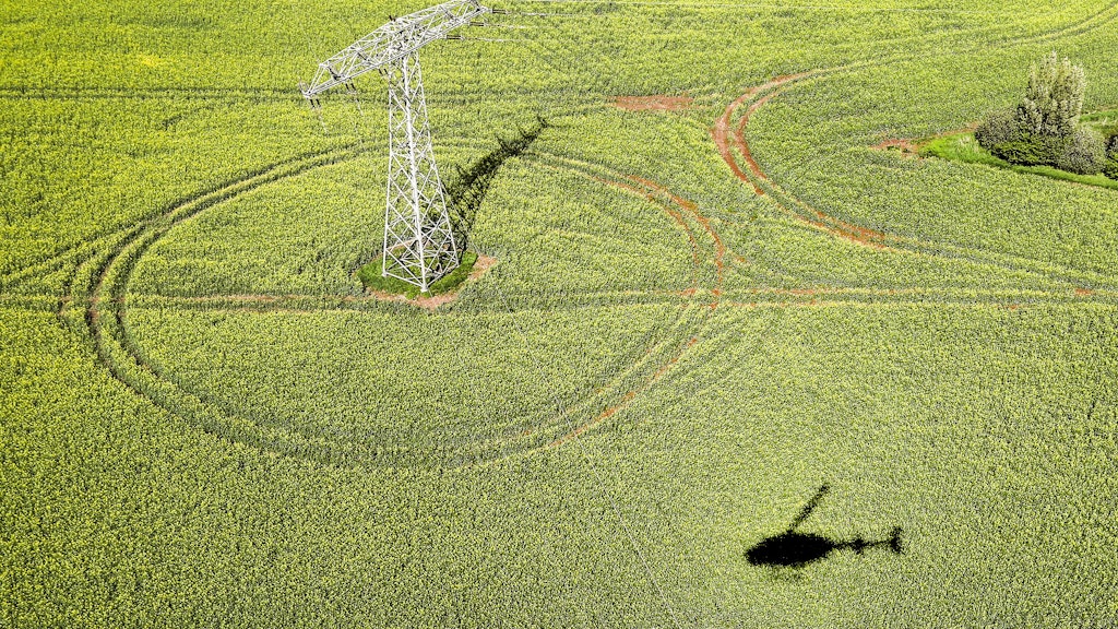 Mit einem Hubschrauber vom Typ Bell Jet Ranger III wird eine Hochspannungsleitung aus der Luft kontrolliert. Bald soll er Unterstützung von Drohnen bekommen.