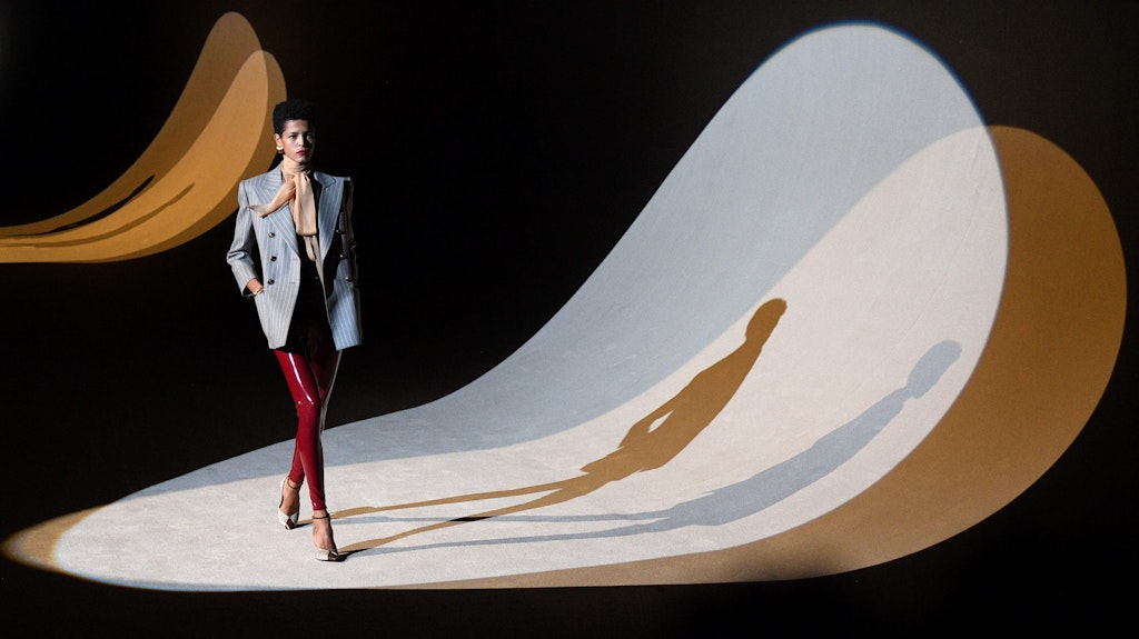 <strong>SAINT LAURENT</strong> holt die Latex-Leggings aus der Schmuddelecke. Obenrum triumphiert der Blazer-über-Schluppenbluse-Charme der Bourgeoisie. 