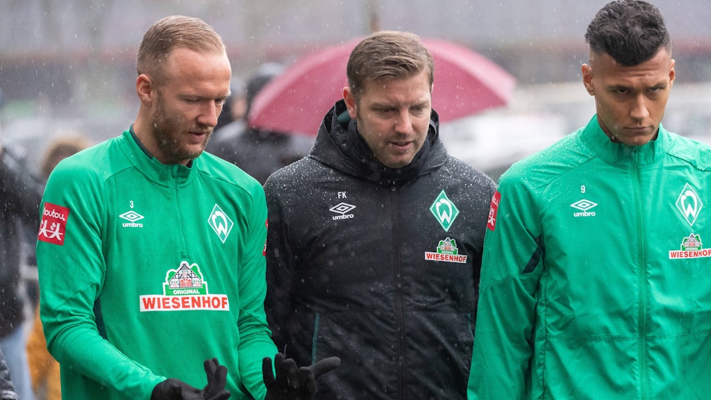 Reden im Regen: Die Bremer Kevin Vogt (l.) und Davie Selke mit ihrem Trainer Florian Kohfeldt. Das Team steht im Pokal und vor dem Bundesligaspiel gegen Union unter Druck
