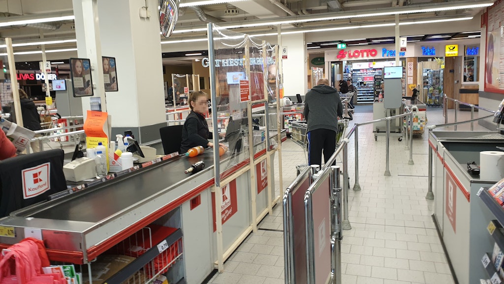 Diese Kassiererin soll durch eine Trennwand vor einer Tröpfcheninfektion geschützt werden.
