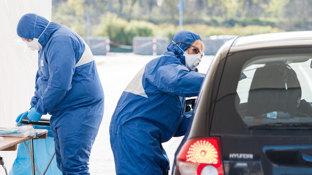 Zwei Ärzte nehmen in einer Drive-In Teststation in Saarlouis auf einem Parkplatz der Ford Werke Abstriche, um sie dann auf das Coronavirus zu testen.