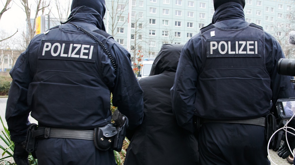Einsatzkräfte der Polizei führen einen Tatverdächtigen in Mitte ab.