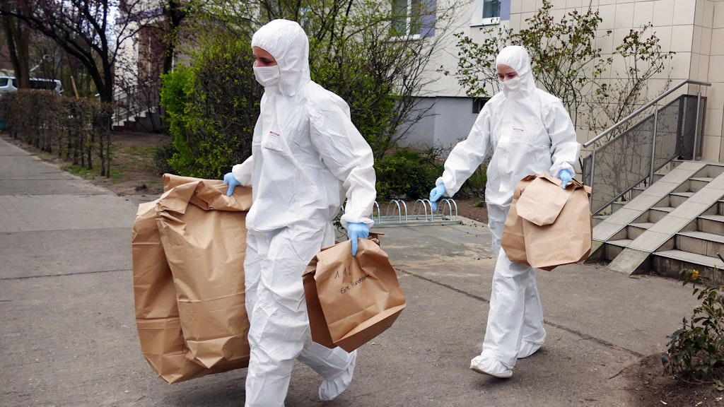 Spezialisten der Spurensicherung tragen am Dienstag in Tüten gesichertes Beweismaterial aus dem Tathaus in der Borkheider Straße in Marzahn.