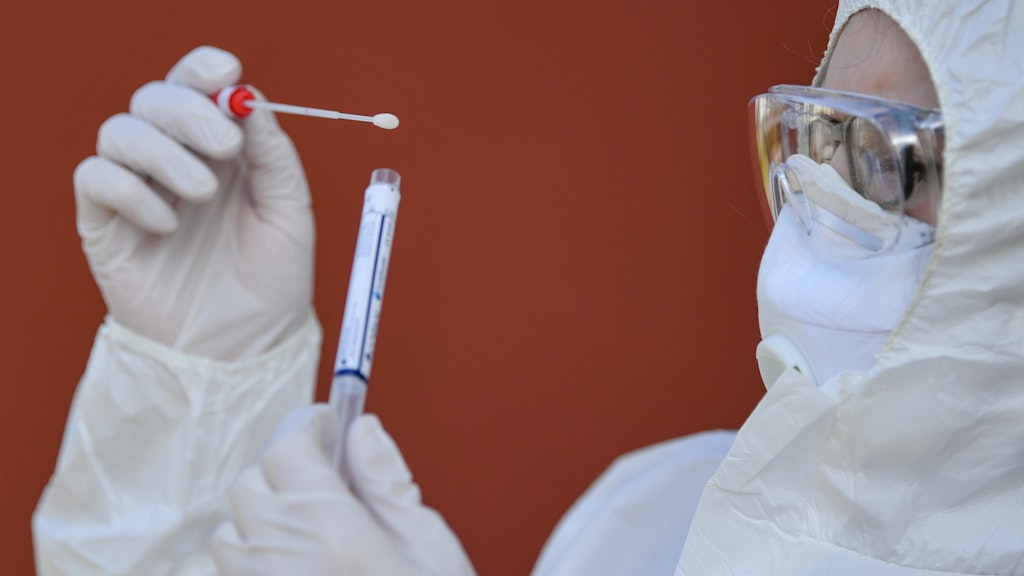 Eine Arzthelferin in Schutzausrüstung hält einen Abstrichtest auf das Coronavirus Sars-Cov-2 in ihren Händen.