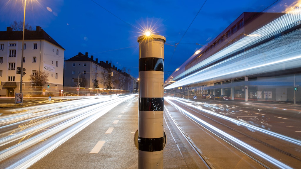 Eine Blitzsäule mit kombinierter Überwachung von Rotlicht und Geschwindigkeit steht an einer Ampelkreuzung.