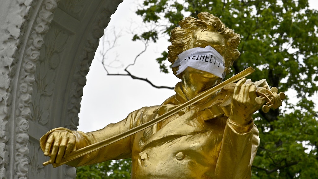 Die Statue des Johann-Strauß-Denkmals im Wiener Stadtpark mit Mundschutz.