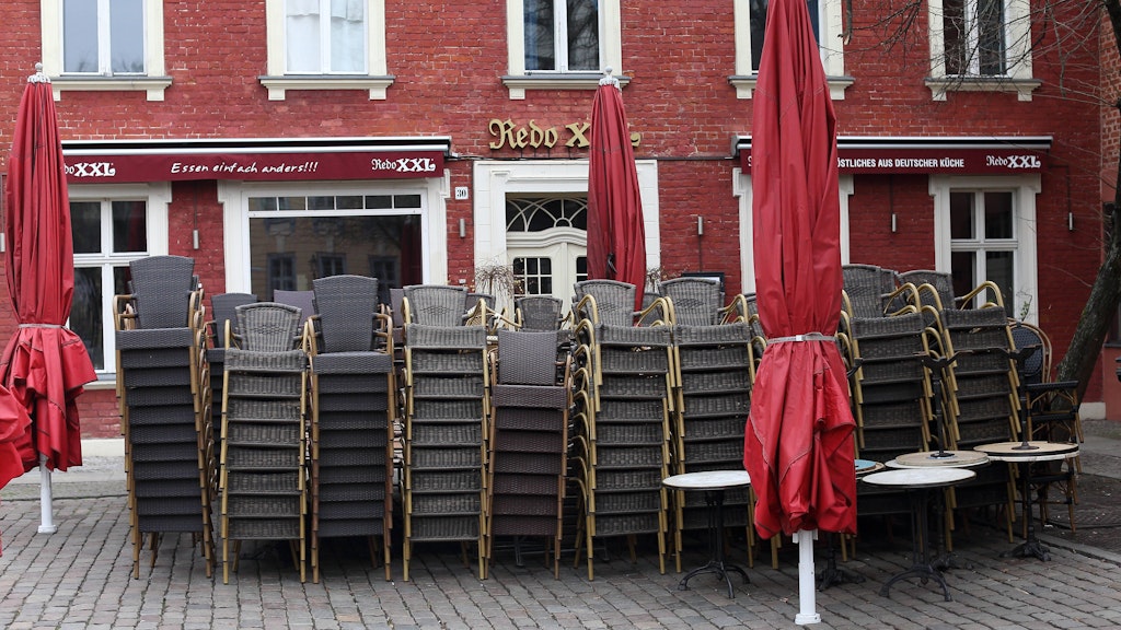 Gestapelte Stühle und Tische vor einem geschlossenen Restaurant.