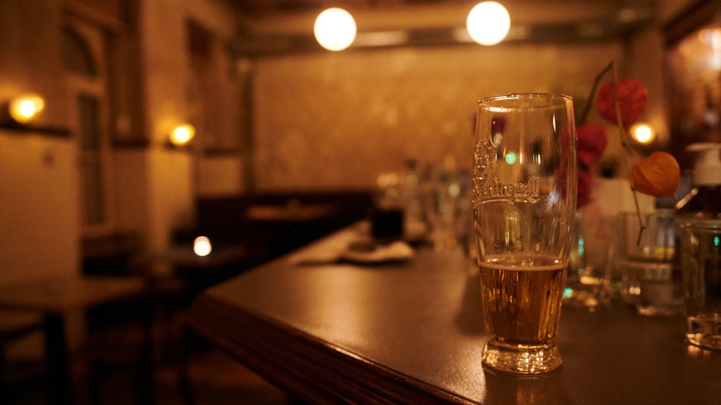  Ein halb geleertes Bier und andere benutzte Gläser stehen kurz nach der Sperrstunde in einer Bar in Neukölln auf dem Tresen. 