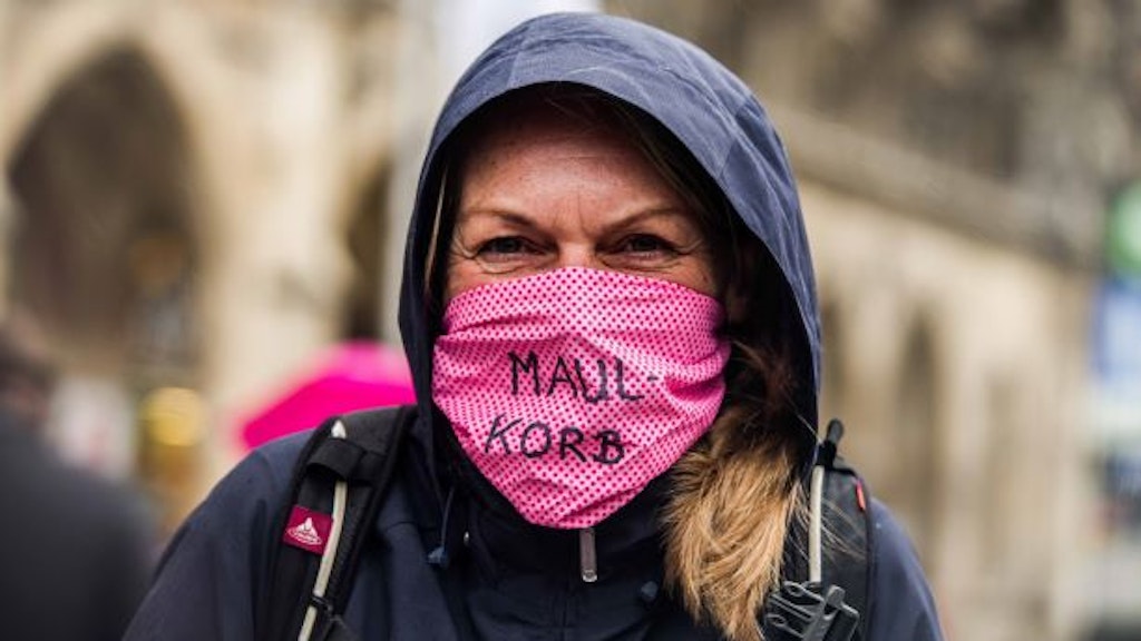 Eine Frau in München trägt eine Maske, auf der das Wort Maulkorb steht.