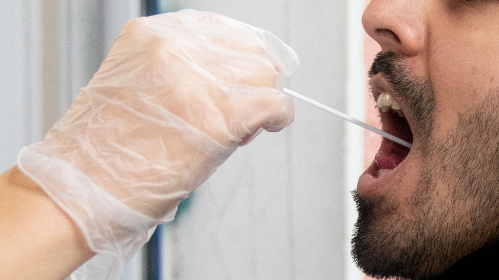 Ein Patient lässt vor einer Arztpraxis einen Abstrich für einen PCR Corona-Test machen