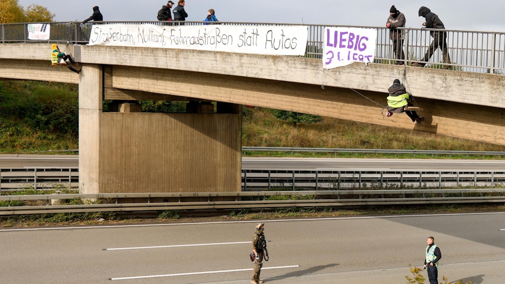 Aktivisten hängen an einer Brücke über der Autobahn 3 ein Plakat auf, auf dem steht: „Liebig 34 lebt“.