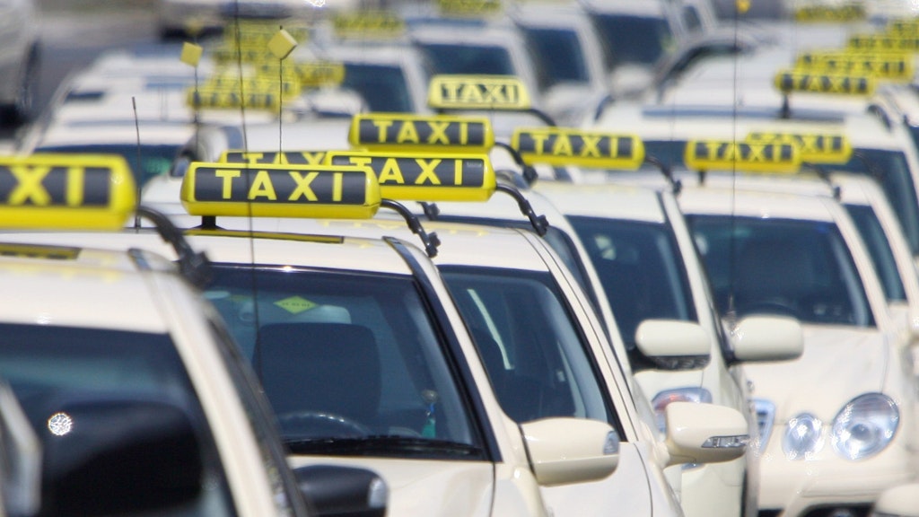 Mehrere Berliner Taxis stehen am Rande einer Demonstration. 