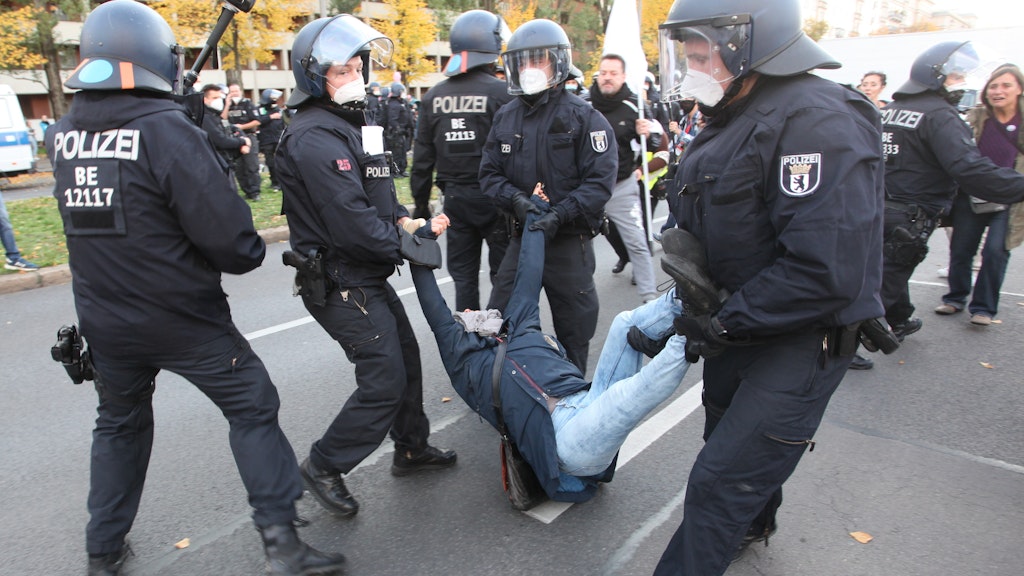 Eine Demonstrantin wird in der Karl-Marx-Alle von der Polizei fortgetragen.