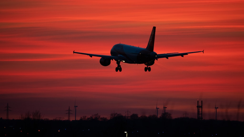 Ein Flugzeug landet bei rotem Abendhimmel auf dem Flughafen Schönefeld. (Symbolbild)