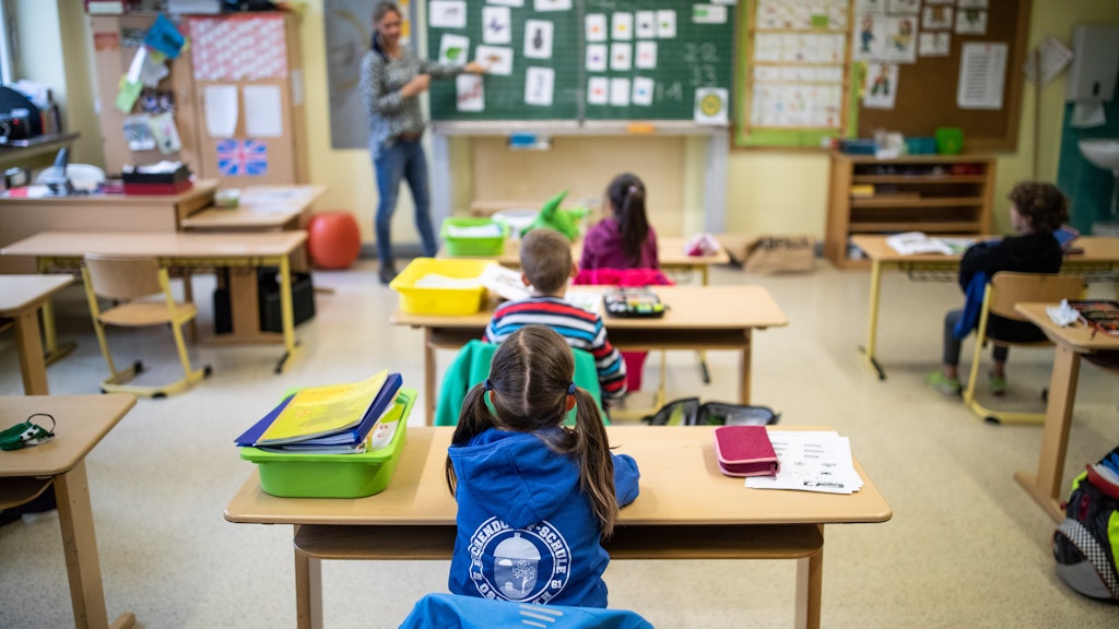 Schülerinnen und Schüler einer Grundschulklasse sitzen mit Abstand in ihrem Klassenraum.