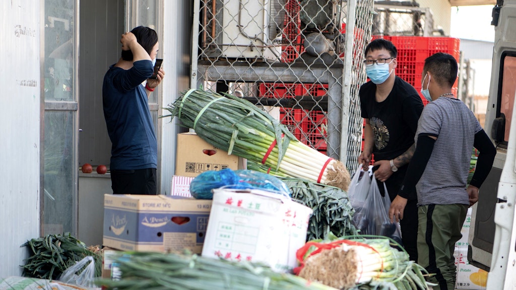 Arbeiter stapeln Gemüse auf einem Markt in Peking.