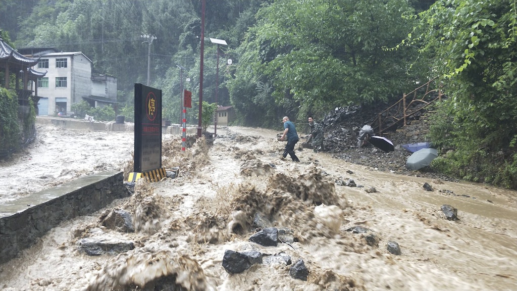 China, Chongqing: Mitarbeiter der Kommunalverwaltung versuchen am 12.06.2020 einen durch Wassermassen beschädigten Deich zu verstopfen.
