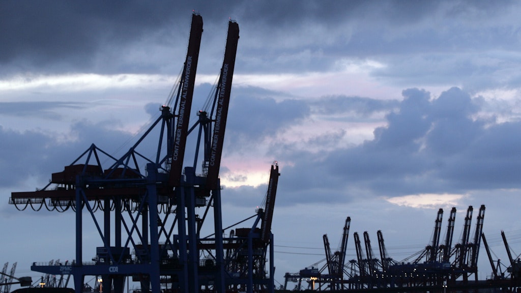 Hochgeklappte Containerbrücken stehen unter einem dunklen, wolkenverhangenen Himmel am Containerterminal Hamburg Altenwerder.