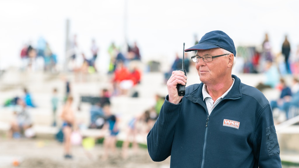 Georg Ulrichs, Angestellter der WSB-Sicherheitsdienst GmbH, steht am Badestrand von Norddeich und spricht über ein Funkgerät mit einem Kollegen. 