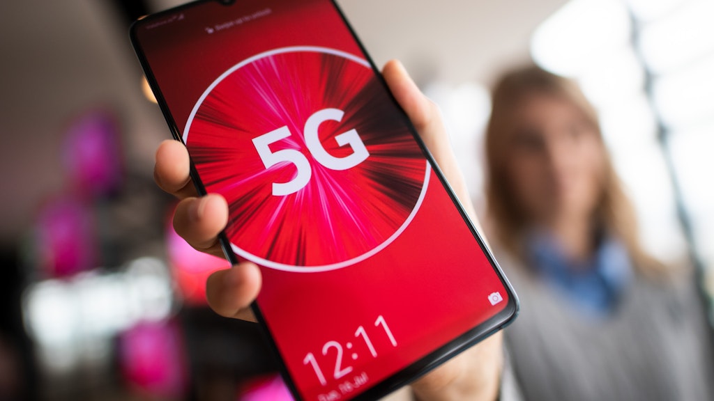 Eine Vodafone-Mitarbeiterin hält ein 5G-Smartphone in der Hand.