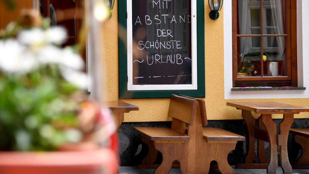 Eine Tafel mit der Aufschrift „Mit Abstand der schönste Urlaub“ ist vor einem Lokal in St. Wolfgang am Wolfgangsee zu sehen.