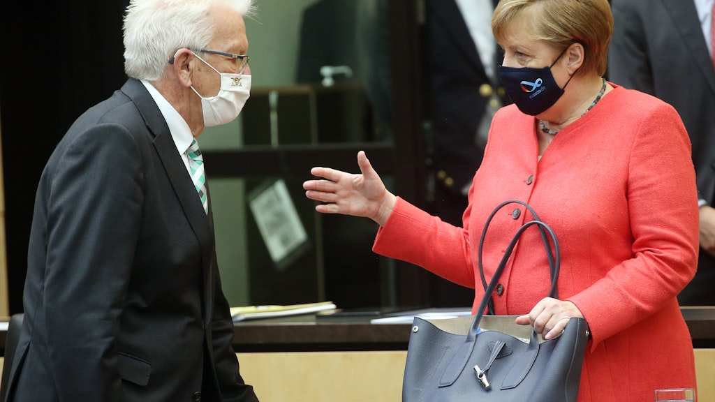 Mit Mund- und Nasenschutzmasken unterhalten sich Bundeskanzlerin Angela Merkel (CDU) und Winfried Kretschmann (Bündnis90/Grüne)