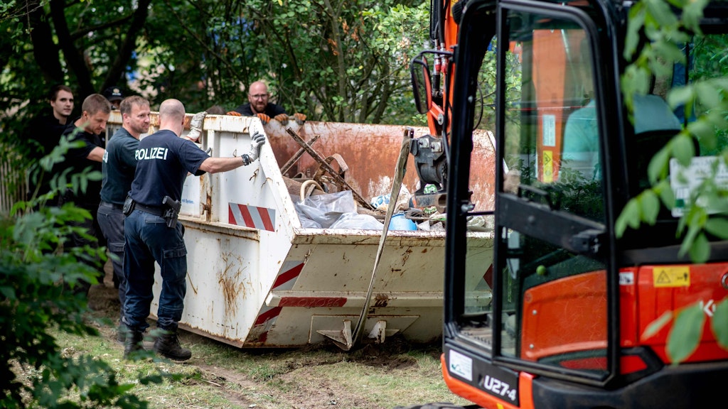 Einsatzkräfte der Polizei an einem Container, in dem gefundene und ausgegrabene Gegenstände im Fall Maddie McCann gesammelt werden.