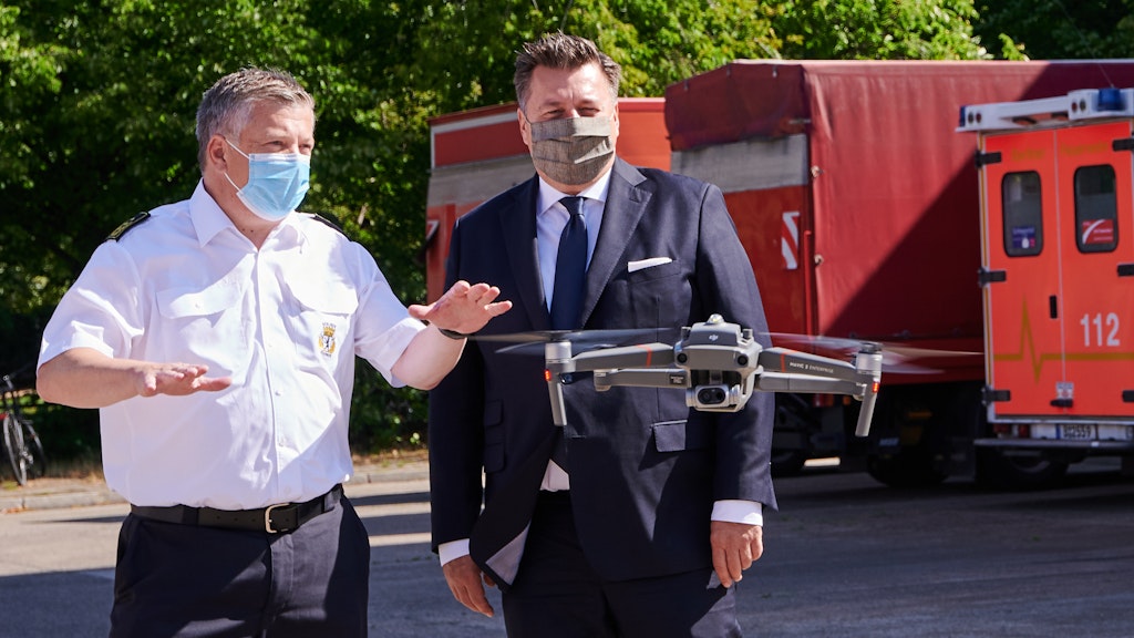 Karsten Homrighausen (l.), Leiter der Berliner Feuerwehr und Landesbranddirektor, spricht mit Innensenator Andreas Geisel (SPD) über die neue Drohne, die vor ihnen schwebt.
