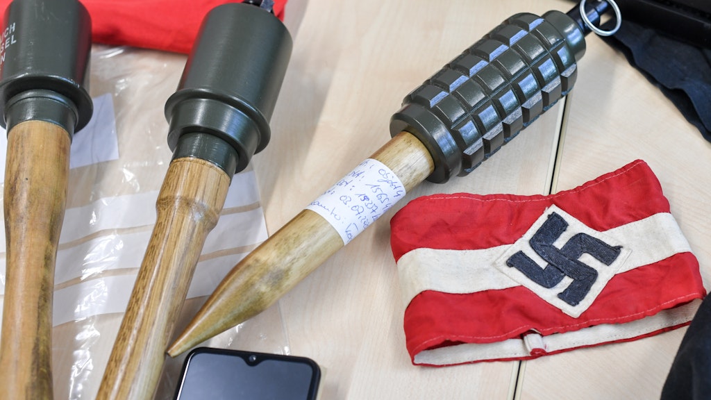 Sichergestellte Handgranaten und Materialien, darunter auch eine Armbinde mit einem Hakenkreuz, liegen bei einem Pressetermin im LKA Brandenburg auf einem Tisch nach einer Razzia gegen die Neonazi-Gruppe „Freie Kräfte Prignitz".
