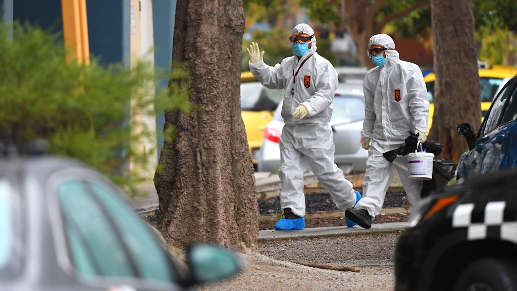 Zwei Personen in Melbourne in Schutzanzügen am Montag auf dem Weg zu einem Gebäude, in dem es zu mehreren Corona-Infektionen gekommen sein soll.