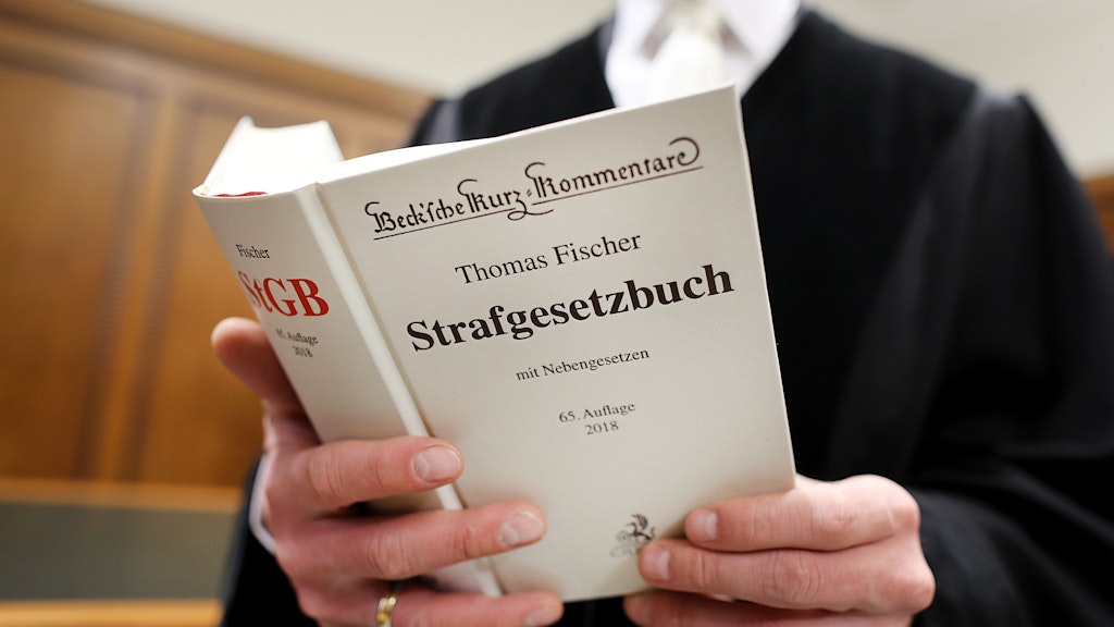 Ein Jurist hält ein Strafgesetzbuch in der Hand. 