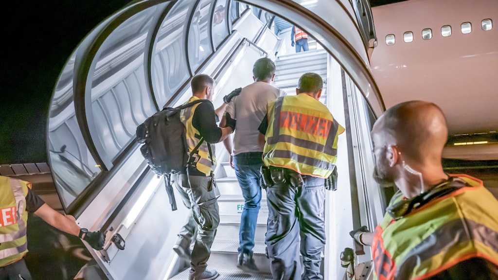 Polizeibeamte begleiten einen Afghanen auf dem Flughafen Leipzig-Halle in ein Charterflugzeug. (Archiv)
