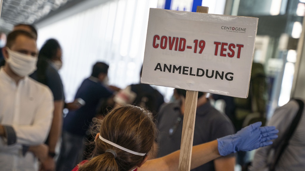 Eine Bedienstete weist in einem Terminal des Frankfurter Flughafens den Weg zur Anmeldung für einen Corona-Test. 
