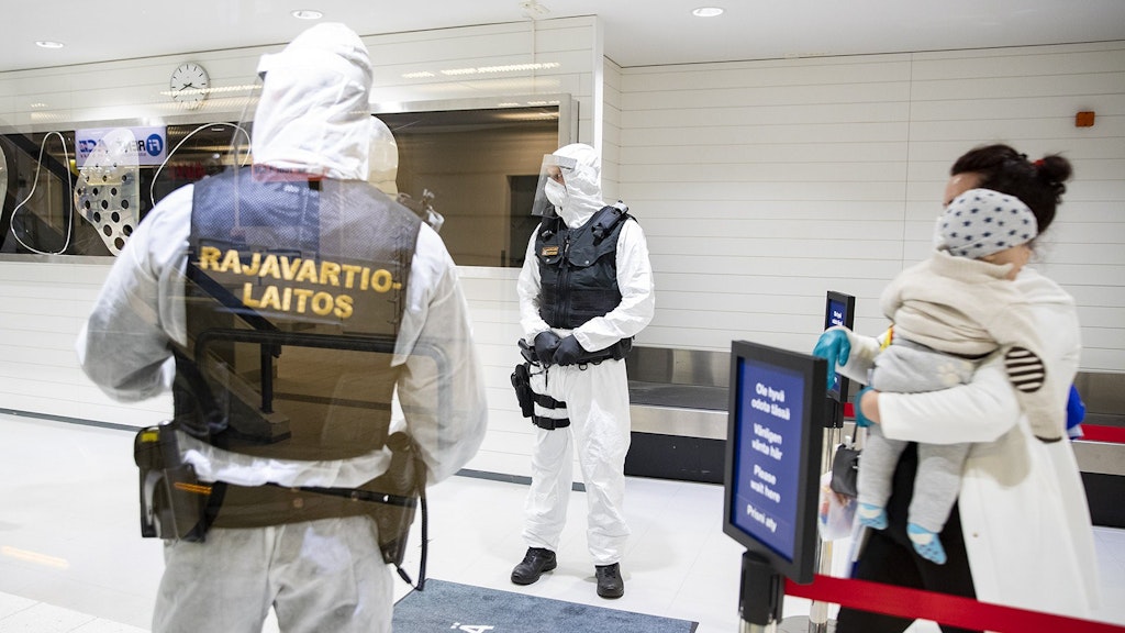 Finnische Grenzschutzbeamte stehen in Schutzkleidung am Flughafen in Turku.