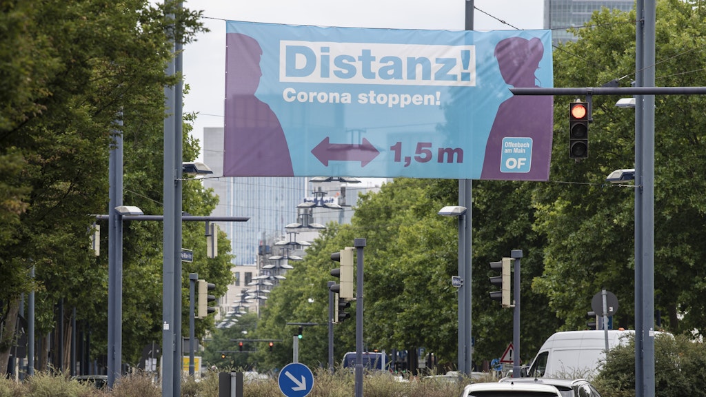„Distanz! Corona stoppen!“ steht auf einem Banner, das über eine Haupteinfahrtstraße nach Offenbach gespannt ist. 