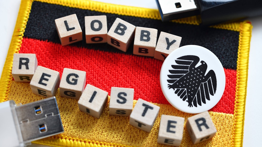 Buchstabenwürfel formen das Wort Lobbyregister auf der Deutschlandfahne.