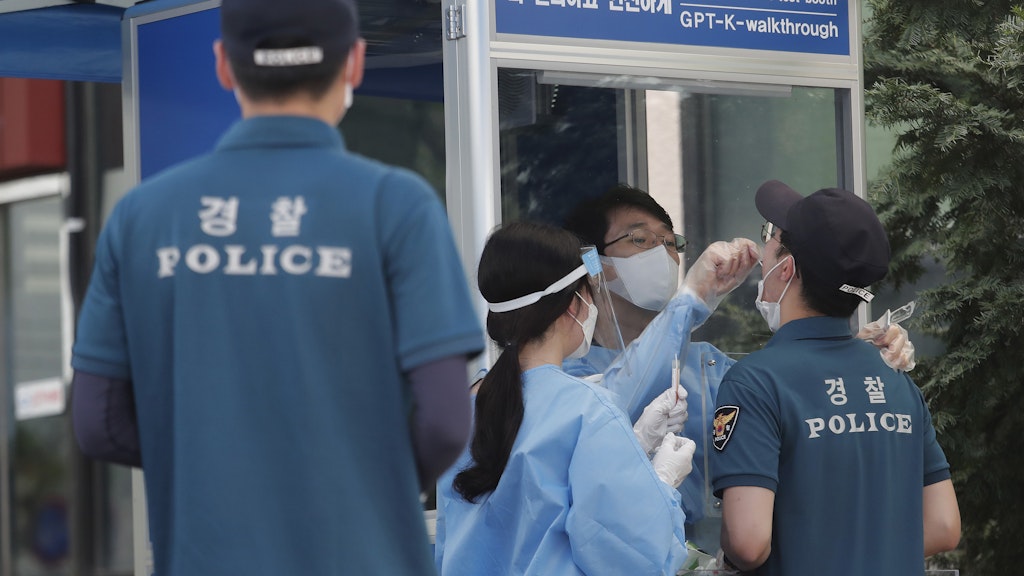 Seoul: Medizinische Mitarbeiter nehmen an einer Corona-Teststation Abstriche von Polizeibeamten.