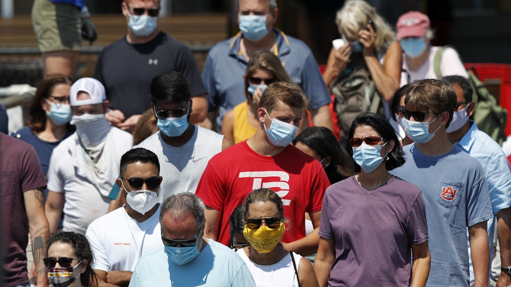 Menschen mit Masken gehen an Bord einer Fähre in Portland, Maine.