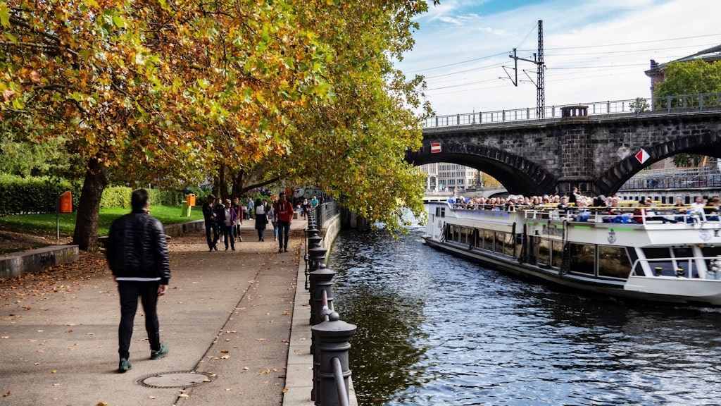 Berliner spazieren bei mildem und sonnigem Wetter im James-Simon-Park an der Spree.