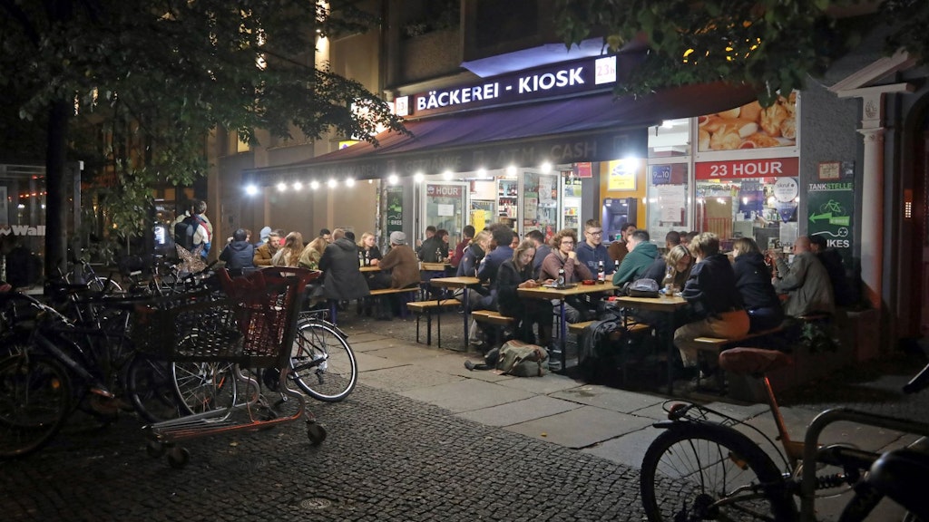 Menschen sitzen nachts vor einem Berliner Späti. Das soll im Bezirk Mitte künftig nicht mehr möglich sein, so das Verwaltungsgericht.