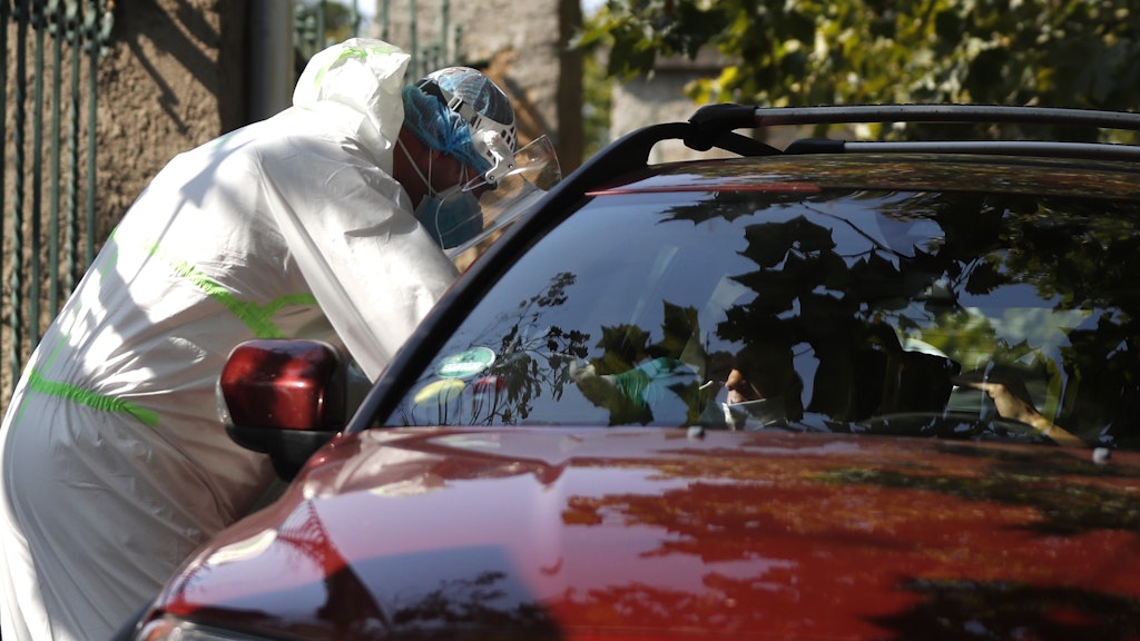 Ein medizinischer Mitarbeiter untersucht einen Autofahrer an einer Drive-in-Teststation in Prag.