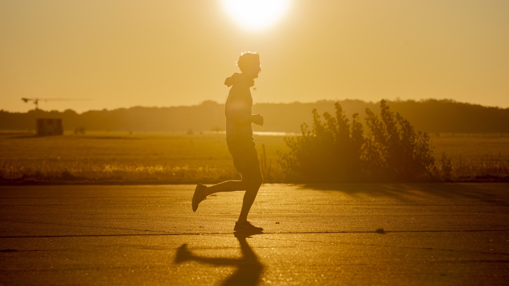Ein Jogger rennt im Licht der Morgensonne über das Tempelhofer Feld.