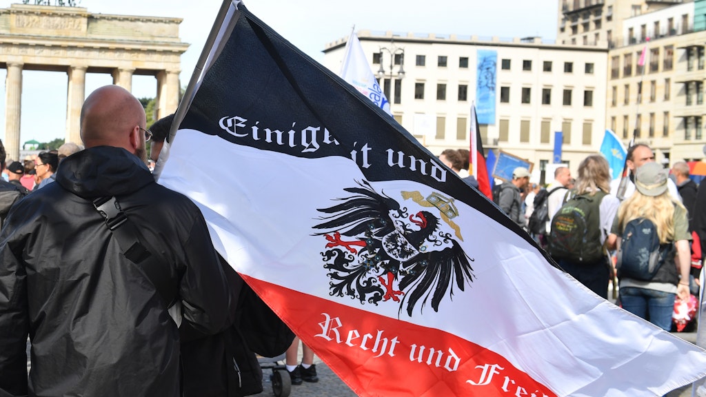 Ein Teilnehmer hält vor einer Demonstration gegen die Corona-Maßnahmen eine Reichsflagge vor dem Brandenburger Tor.