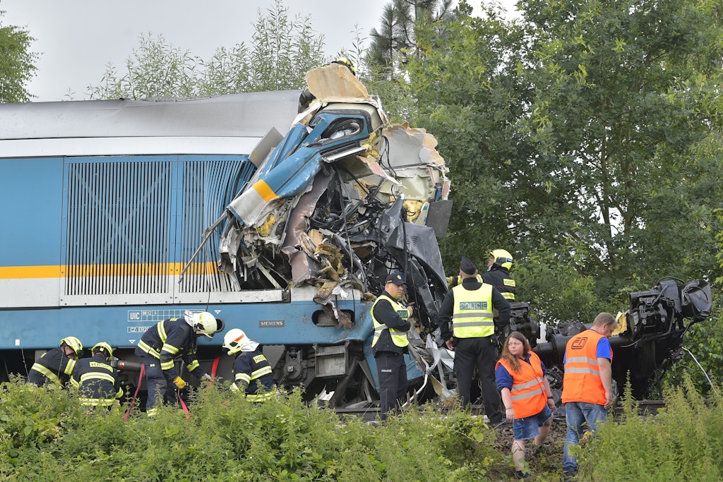 Einsatzkräfte stehen an einem zerstörten Waggon.