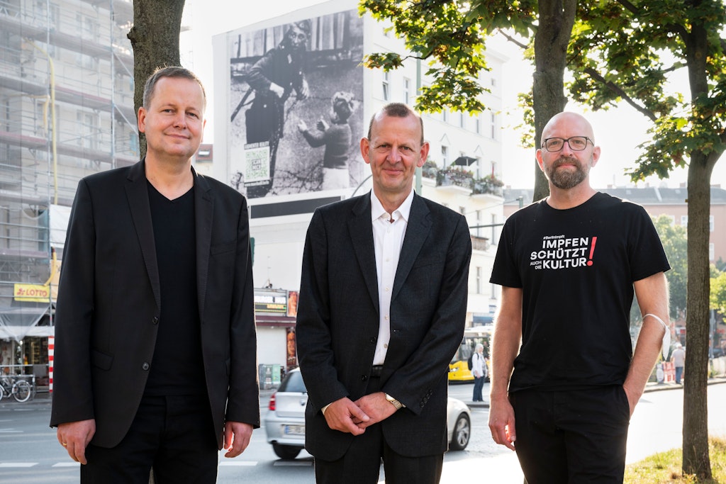 Klaus Lederer, Axel Klausmeier und Moritz van Dülmen (v.l.) vor dem Plakat am Hermannplatz.