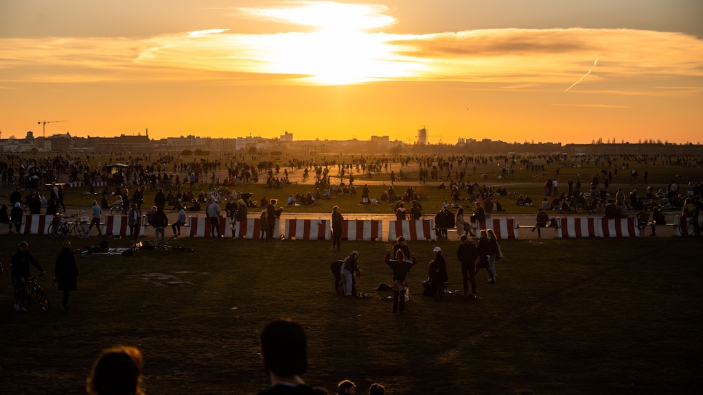 Menschen genießen die untergehende Sonne und frühlingshafte Temperaturen auf dem Tempelhofer Feld.