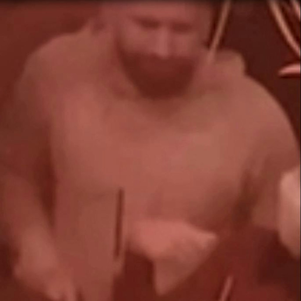 Der gesuchte Mann grinst eine Person in der Bar an. 