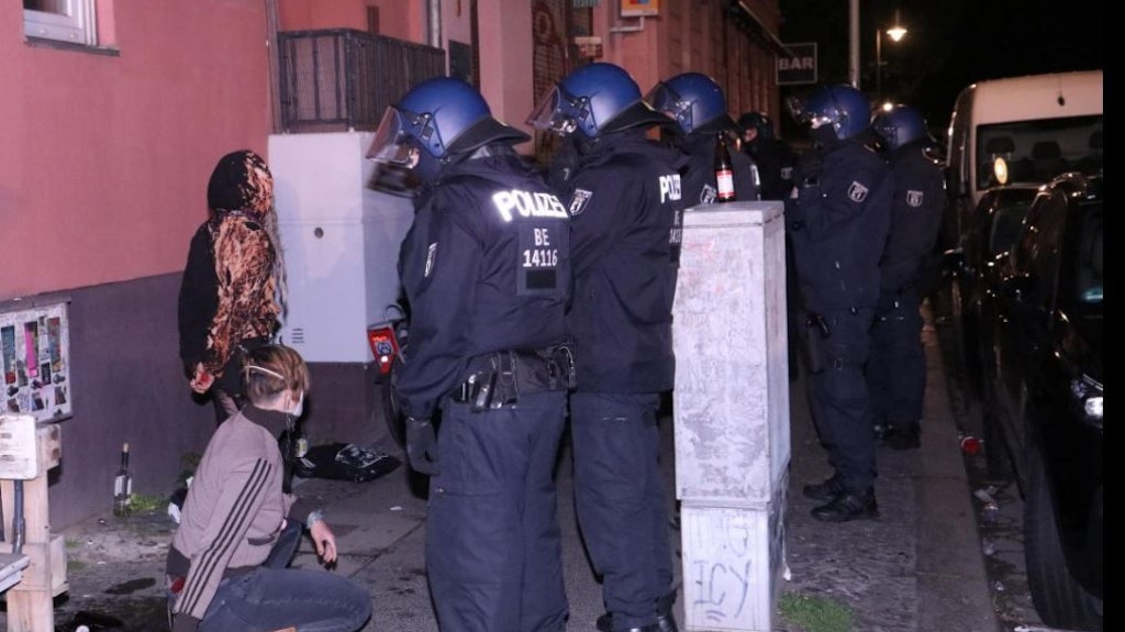 Behelmte Einsatzkräfte der Polizei Berlin stehen zwei jungen Menschen gegenüber.